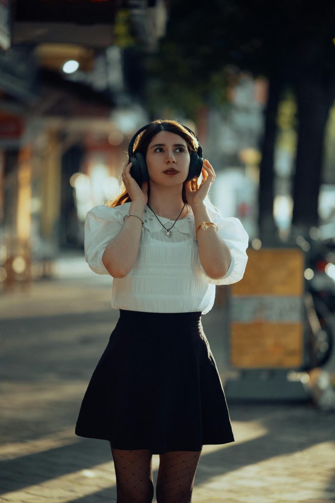 pexels-photo-33919674-33919674 A stylish young woman listens to music with headphones on a sunny fall day outdoors.