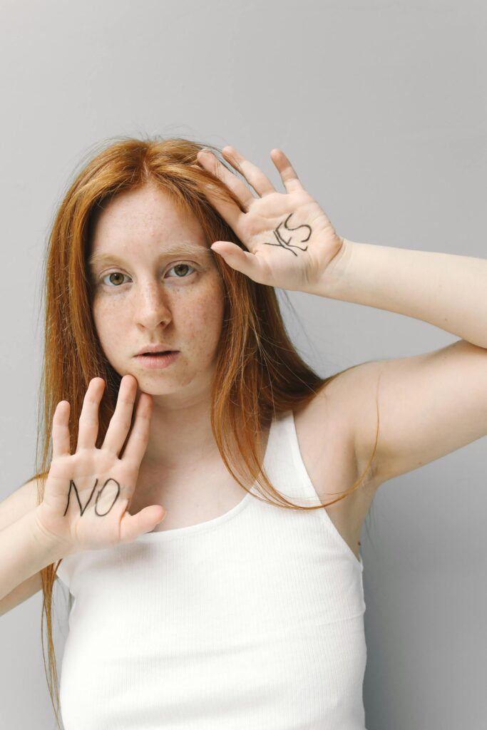 A woman with red hair contrasts 'no' and 'yes' with hand gestures in a white tank top.