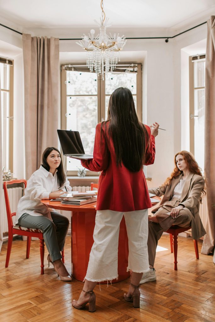 Three professional women in a business meeting, discussing strategies in a modern office setting.